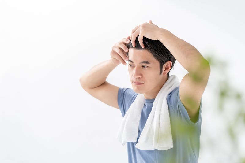 頭髪を気にして詳しくチェックしている男性
