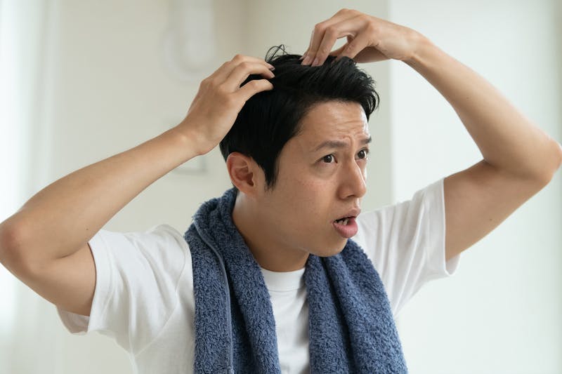 頭皮の状態を気にして念入りにチェックしている男性