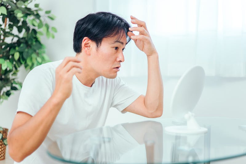 鏡を見てセットする男性