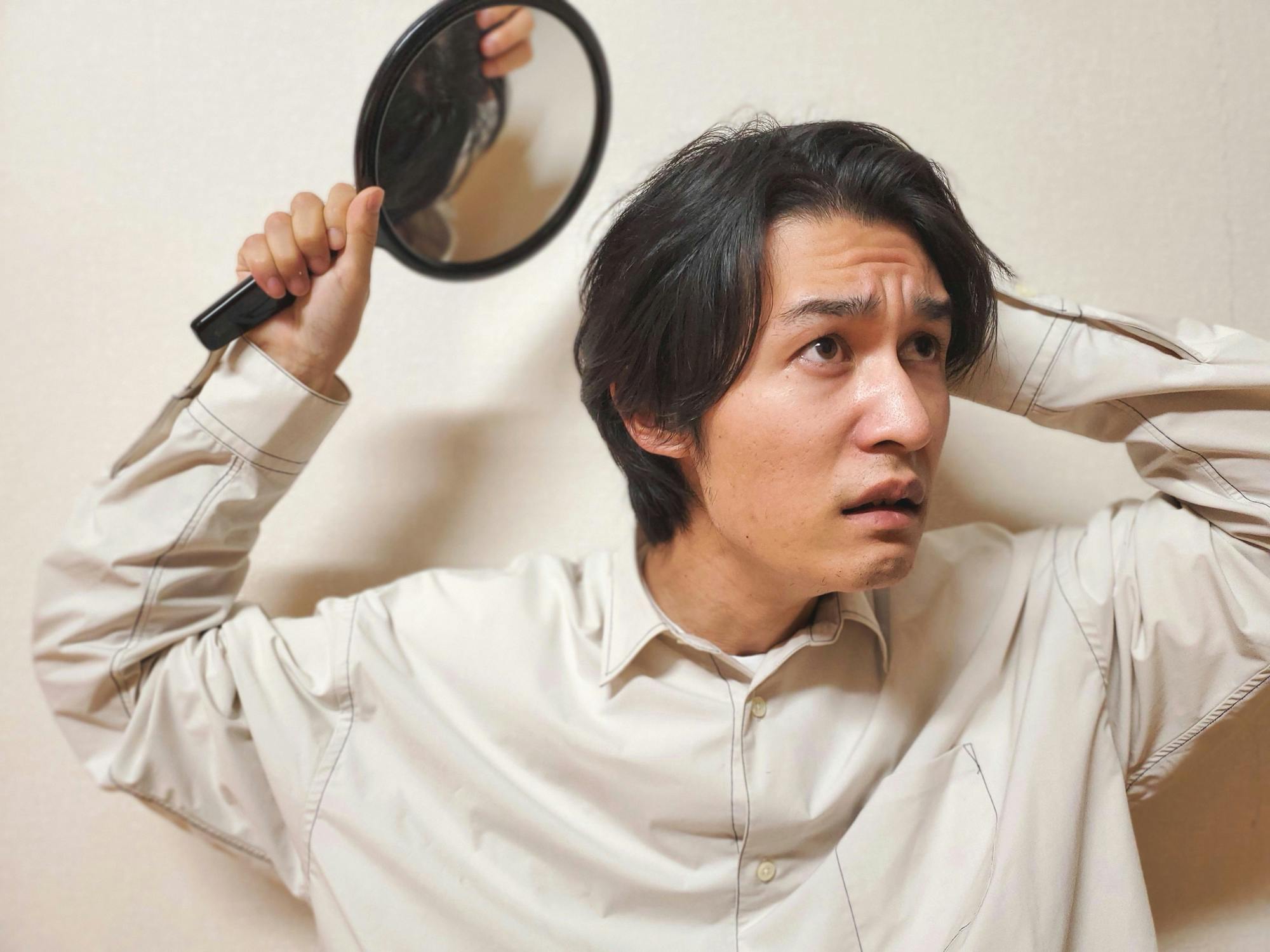 手鏡を使って後頭部をチェックしようとする男性
