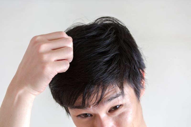 髪の状態を触ってチェックしている男性
