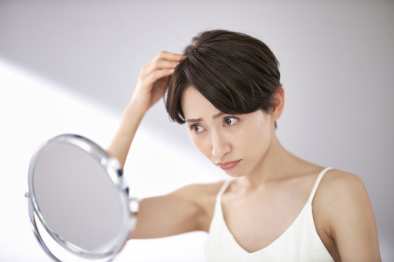 前髪をチェックして悩んでいる女性