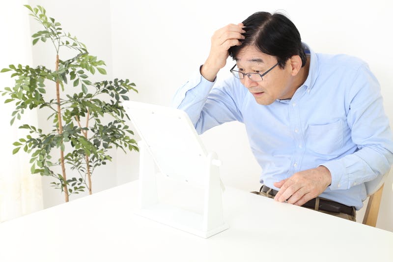 鏡の前で髪の分け目をチェックする男性