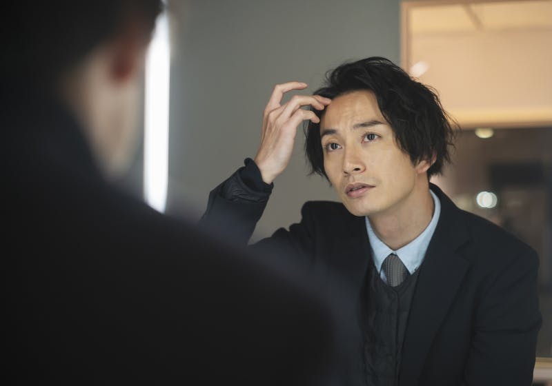 生え際の様子をチェックしている1人の男性