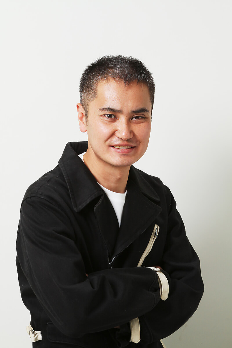 カメラ目線で腕組みをする、すっきりとベリーショートにカットした男性