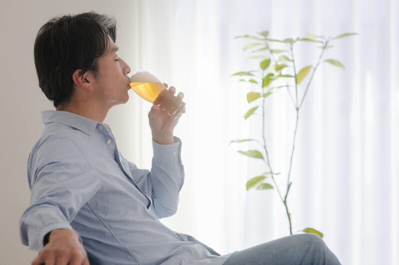 昼間のリビングでビールを飲む男性