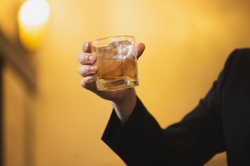 グラスに入ったウイスキーを持つ手