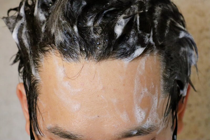 シャンプー中の男性のおでこ・頭部のアップ