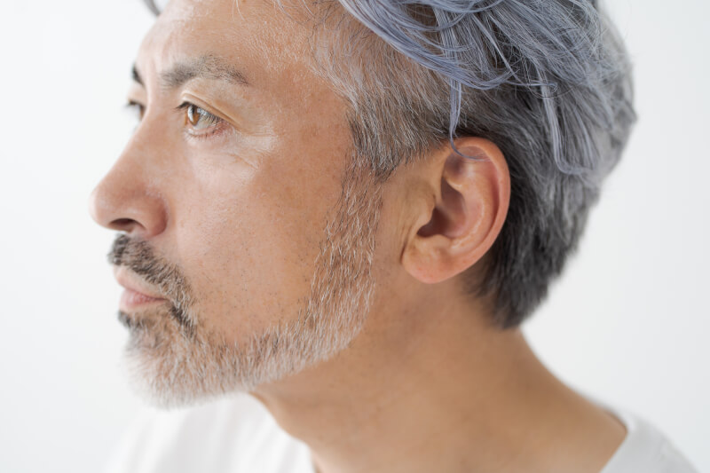 顔の輪郭や口周りのひげを整えたグレイヘアのミドル男性のアップ