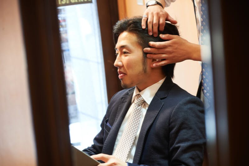 美容師とスタイリングを相談する男性客