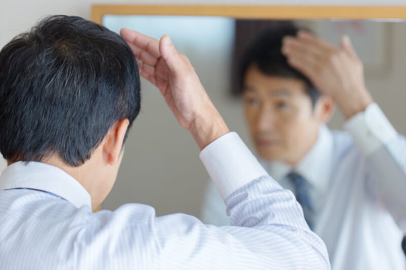 鏡で髪の様子を確認している男性