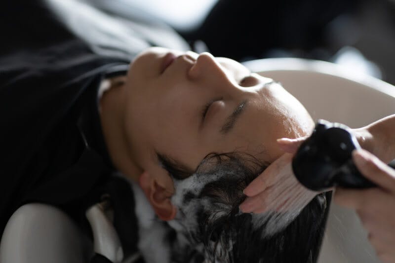 美容室でシャンプーしてもらっている男性