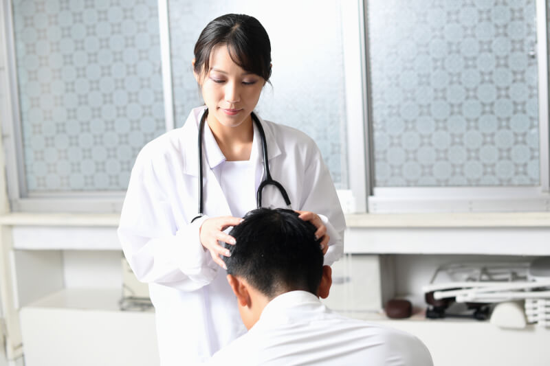薄毛治療の診断をする女性医師と診断を受ける男性の後ろ姿