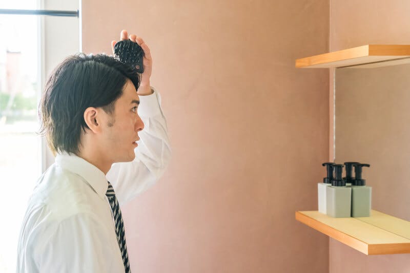 洗面所で頭皮ケアをする男性