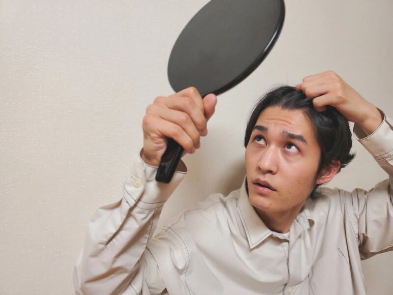 生え際を鏡でチェックする男性