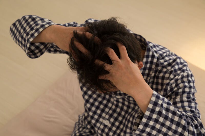 パジャマを着て頭を抱える男性