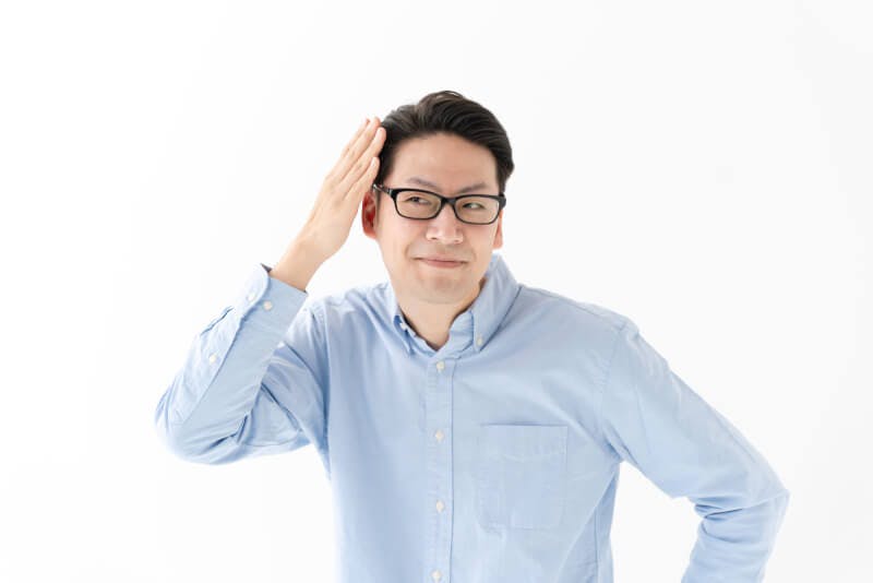 セットした髪を触り微笑むメガネをかけた男性