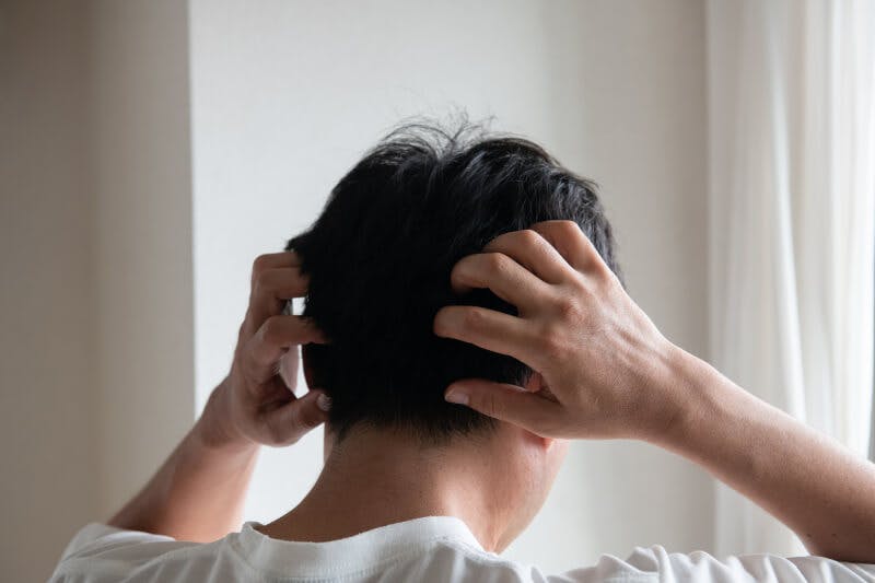 頭皮を指でマッサージしている男性の後ろ姿