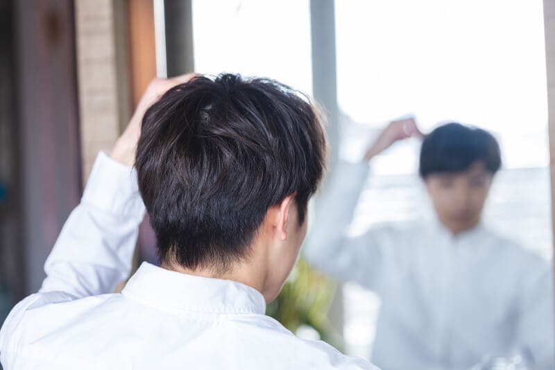 鏡を見ながら髪を整える男性