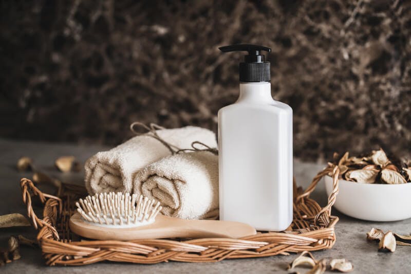 頭皮ケア用のブラシとポンプ式ボトル、タオルが並べられたバスグッズセット